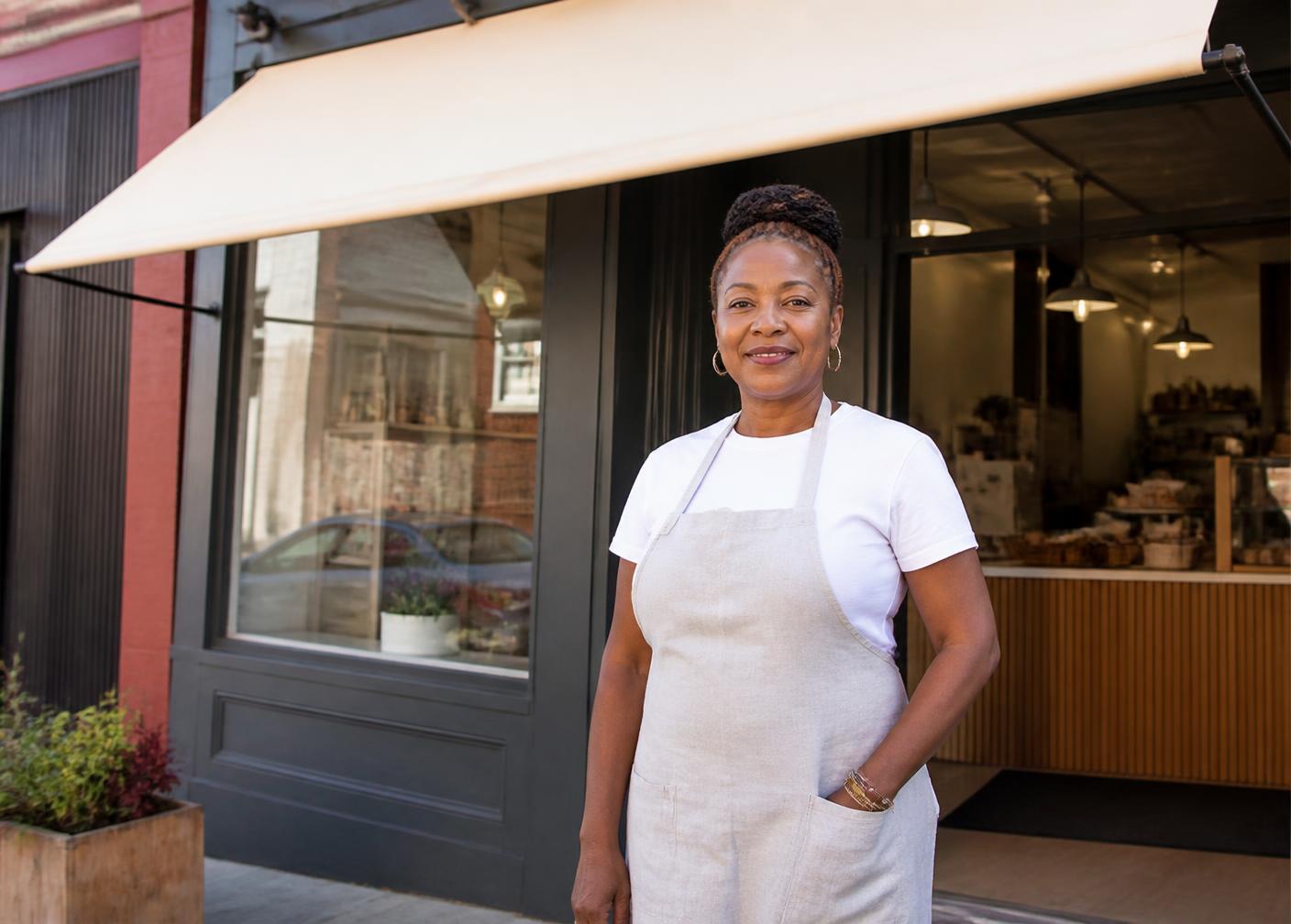 A small business owner standing outside her shop before opening